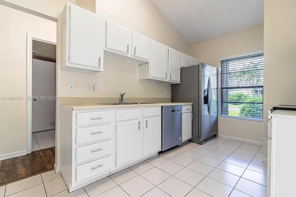 a kitchen with white cabinets and window