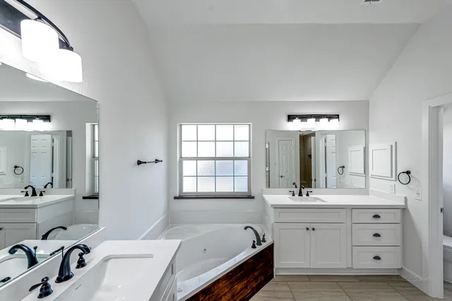 a bathroom with a double vanity sink mirror and bathtub
