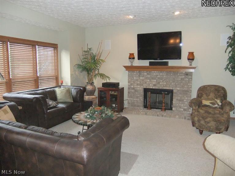 3795 Stonebridge Boulevard Akron, OH 44321 - Photo 9 of 24 The family room features neutral carpet and walls. A brick fireplace is the focal point of the far wall.