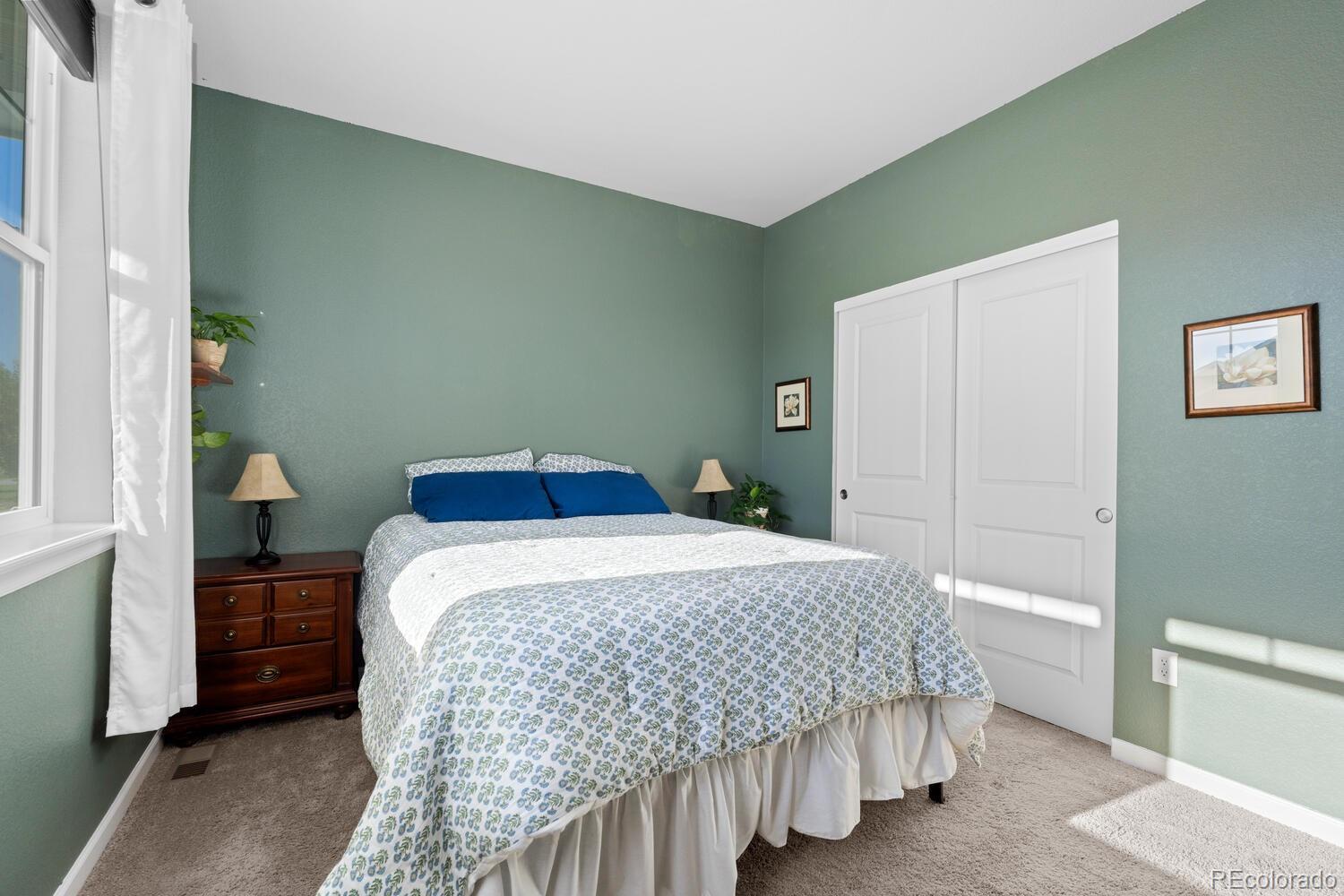 1587 Lake Point Way Severance, CO 80550 - Photo 11 of 40 a bedroom with a bed and a lamp on the dresser