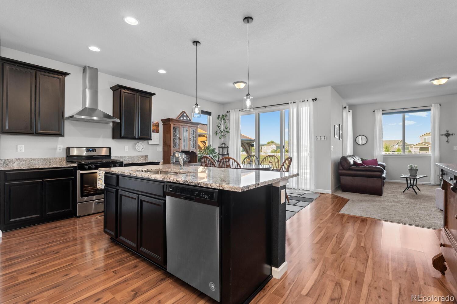 1587 Lake Point Way Severance, CO 80550 - Photo 15 of 40 a kitchen with stainless steel appliances granite countertop a sink stove and wooden floor