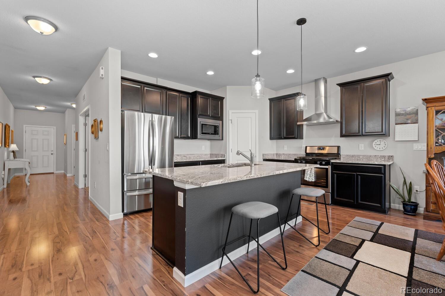 1587 Lake Point Way Severance, CO 80550 - Photo 16 of 40 a kitchen with stainless steel appliances kitchen island granite countertop a stove a sink a refrigerator and a oven