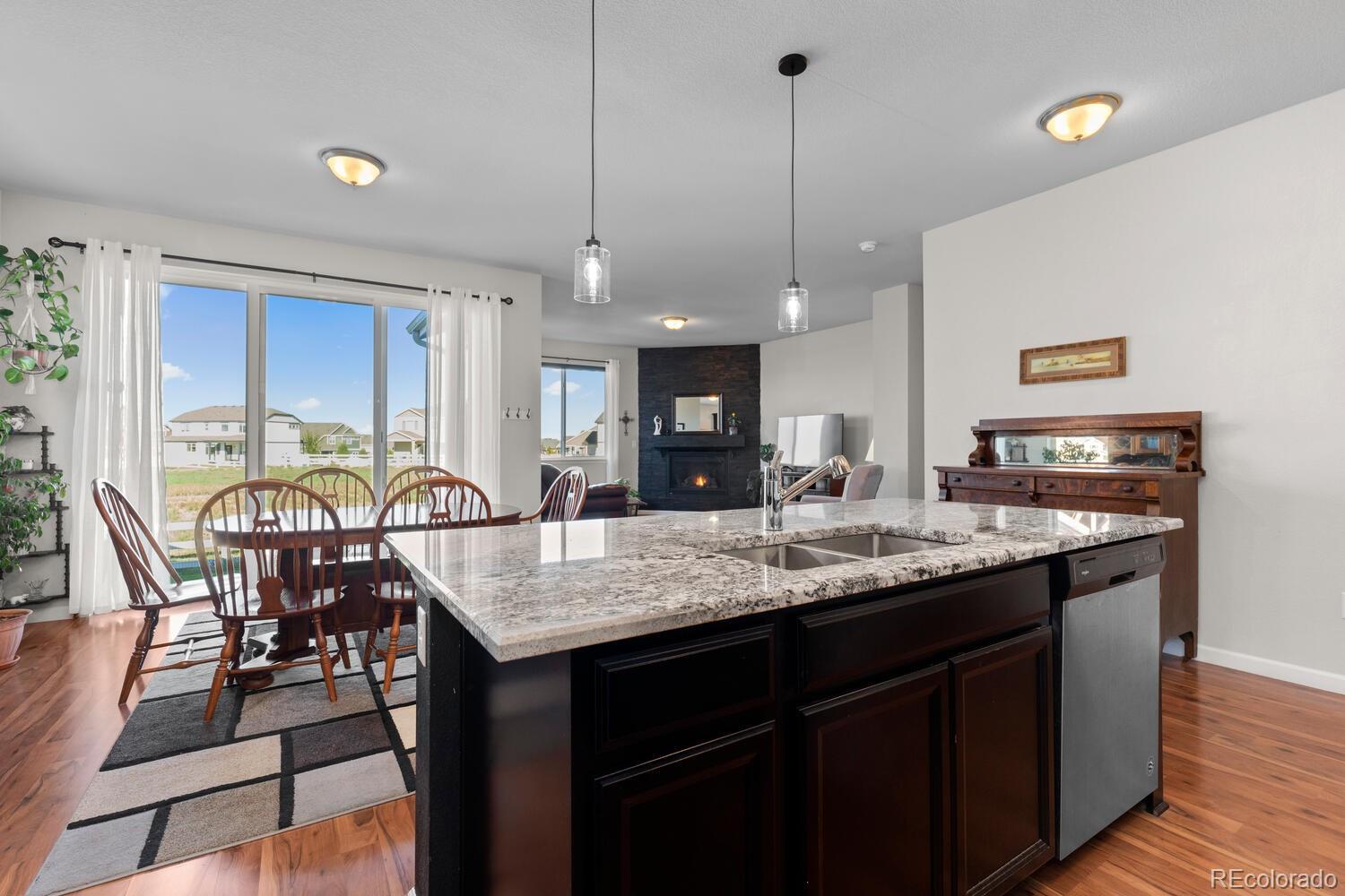 1587 Lake Point Way Severance, CO 80550 - Photo 18 of 40 a kitchen with granite countertop a stove a sink a dining table and chairs with wooden floor