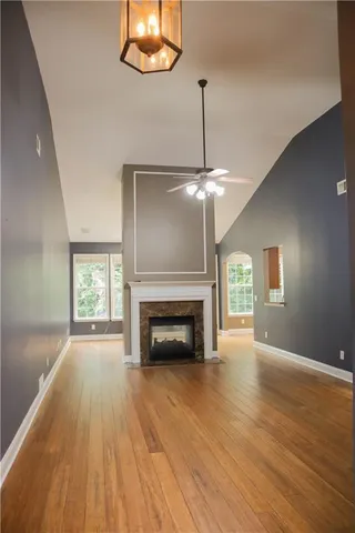 an empty room with wooden floor fireplace and chandelier