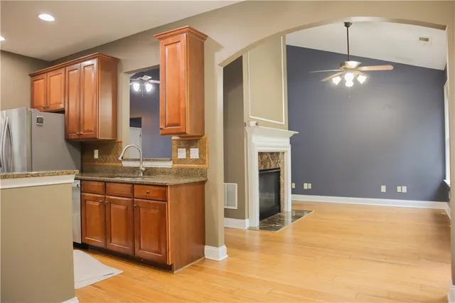 a view of a kitchen with kitchen island granite countertop wooden floor and stainless steel appliances