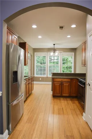 a kitchen with stainless steel appliances granite countertop a refrigerator a sink dishwasher a stove and white countertops with wooden floor