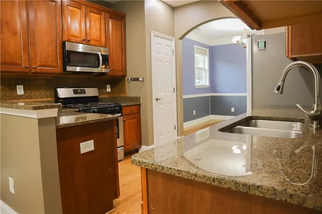 a kitchen with granite countertop a sink a stove and cabinets