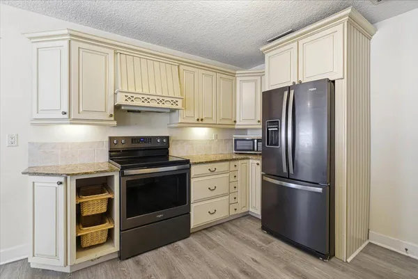 a kitchen with stainless steel appliances granite countertop a refrigerator stove and cabinets