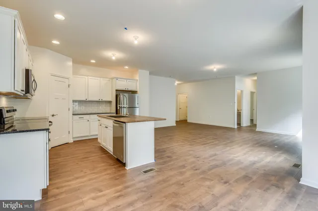 a kitchen with kitchen island white cabinets and stainless steel appliances