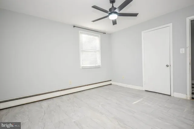 an empty room with a window and a fan