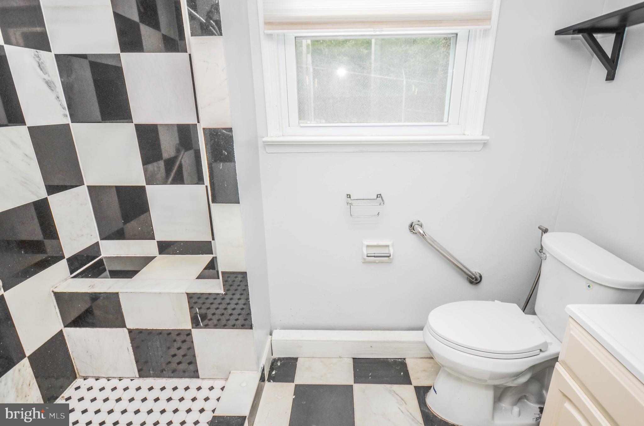 9801 Belhaven Road Bethesda, MD 20817 - Photo 29 of 32 a white toilet sitting next to a bathroom sink and a mirror