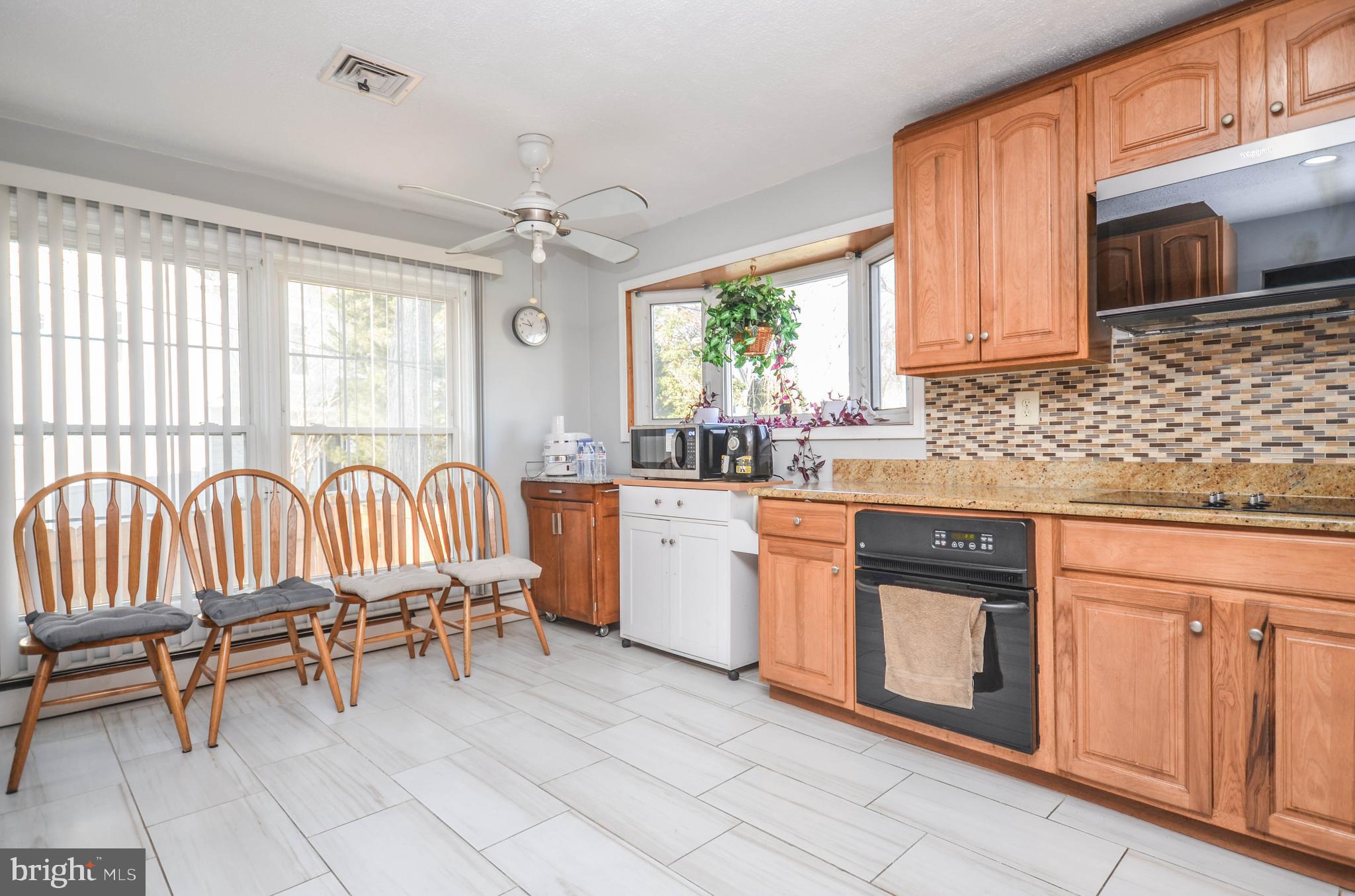 9801 Belhaven Road Bethesda, MD 20817 - Photo 9 of 32 a kitchen with granite countertop a sink dishwasher a stove a oven with a dining table and chairs