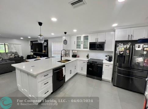 a kitchen that has a lot of white cabinets and stainless steel appliances