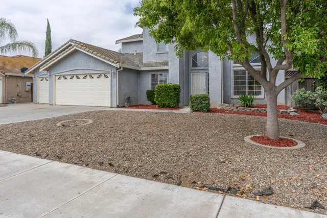 a view of a house with a yard and large tree