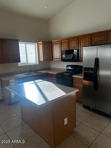 a kitchen with kitchen island granite countertop a sink a stove and a refrigerator