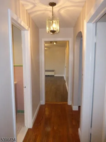 a view of a hallway with wooden floor and a chandelier
