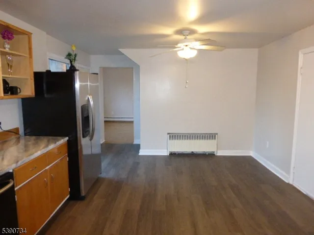 a view of a kitchen with a fridge and wooden floor