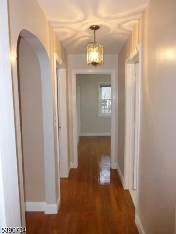 a view of a hallway with wooden floor and a chandelier