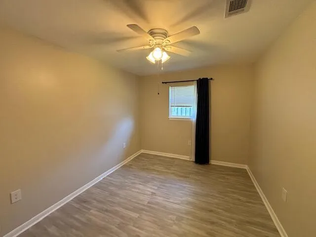 an empty room with a chandelier fan and windows