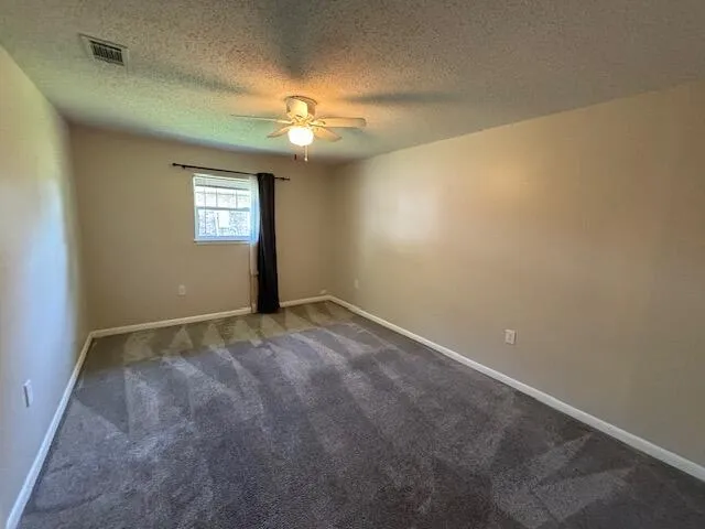 an empty room with a window and chandelier fan