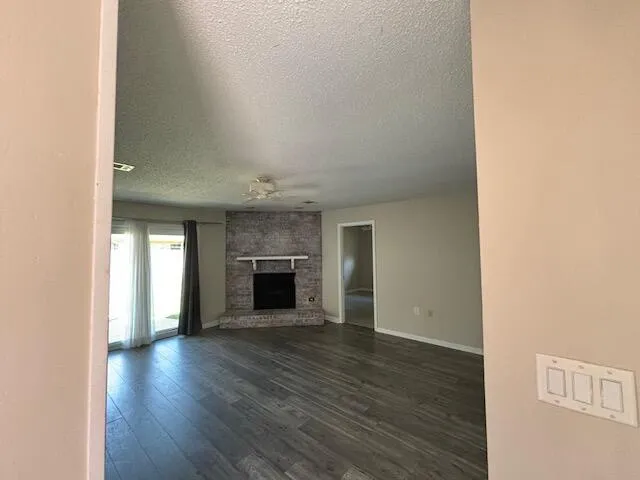 a view of an empty room with wooden floor and a fireplace