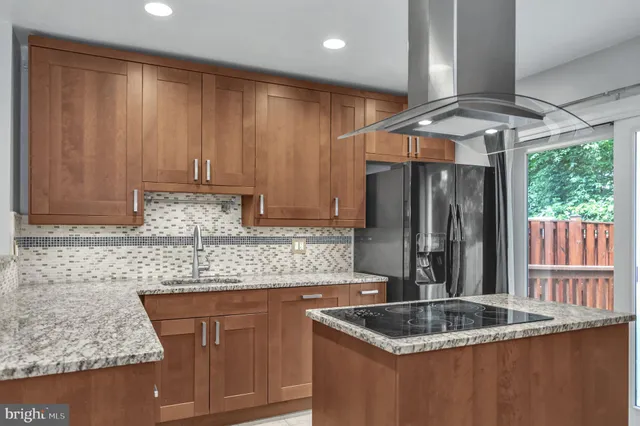 a kitchen with stainless steel appliances granite countertop a sink a refrigerator and wooden cabinets