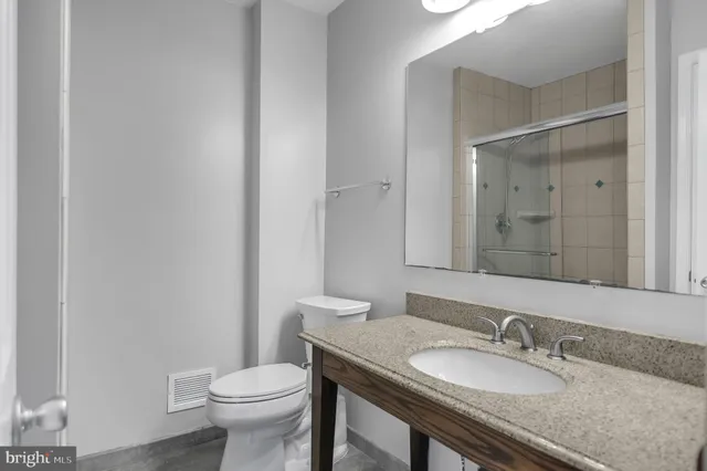 a bathroom with a granite countertop sink a toilet and a mirror