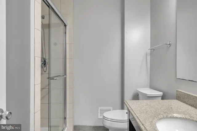 a bathroom with a granite countertop toilet a sink and a mirror