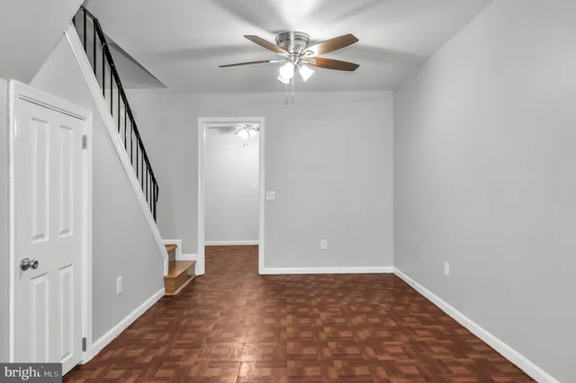 a view of an empty room with stairs and a ceiling fan