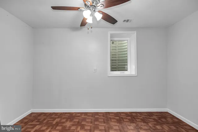 an empty room with a window and a fan