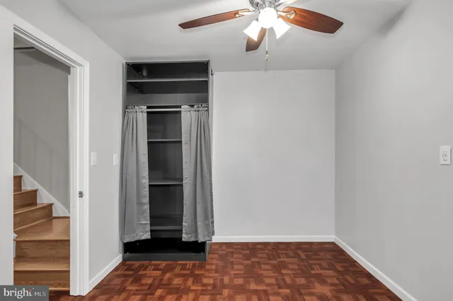 an empty room with wooden floor a ceiling fan and a window
