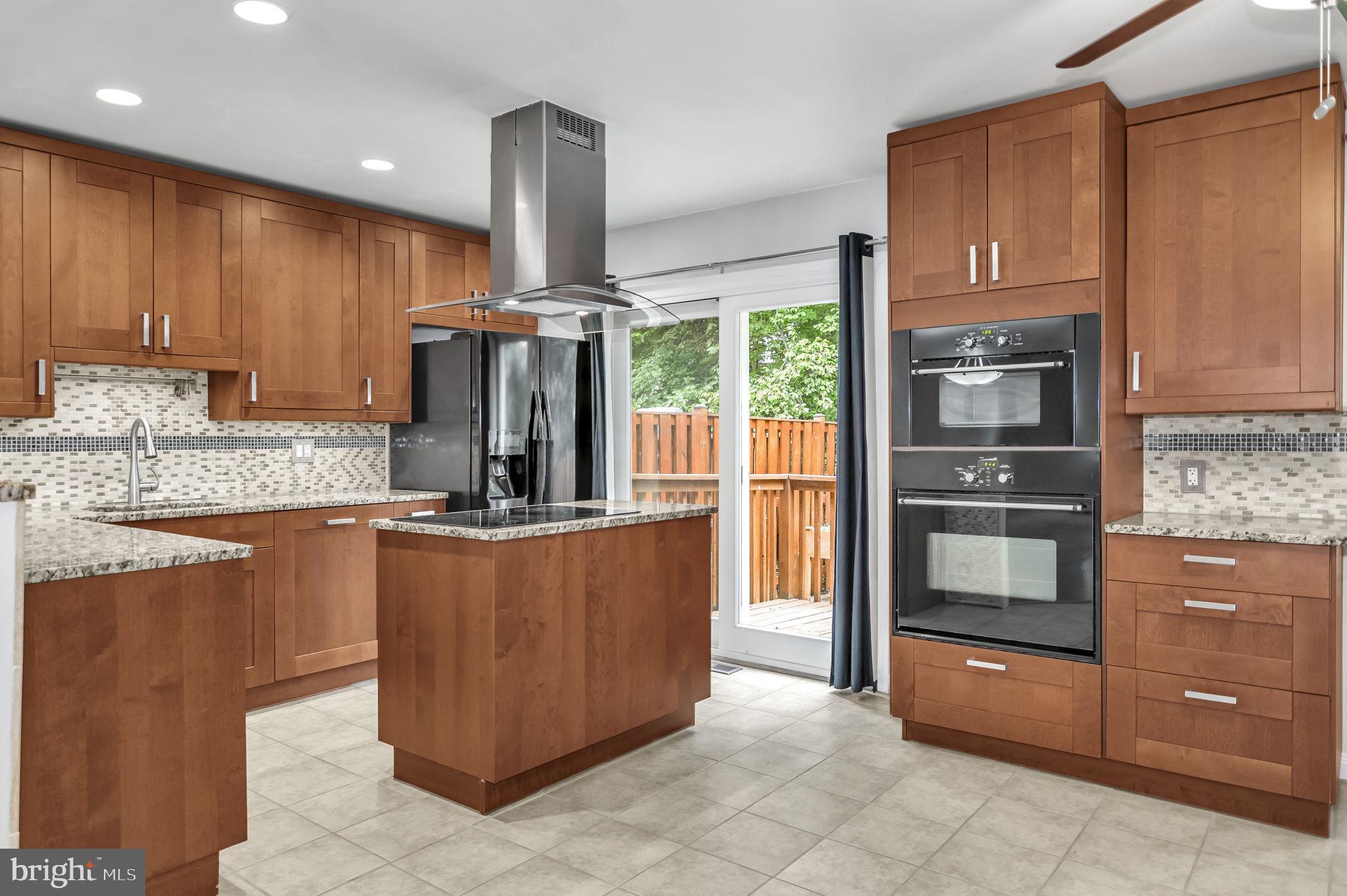8914 Grandstaff Court Springfield, VA 22153 - Photo 9 of 48 a kitchen with kitchen island granite countertop wooden cabinets and stainless steel appliances