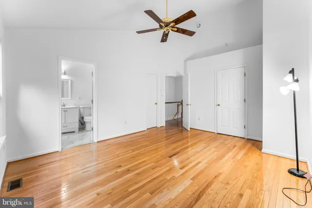 a view of empty room with wooden floor and ceiling fan