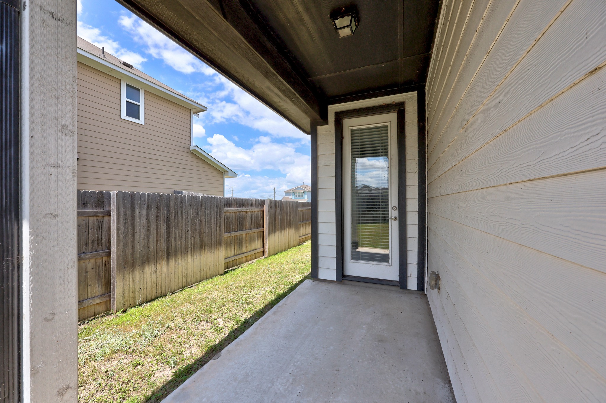 213 Graver Street Georgetown, TX 78626 - Photo 29 of 33 A private concrete patio extends from the back of the house, offering a secluded outdoor space.