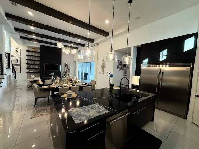 a kitchen with stainless steel appliances kitchen island granite countertop a table chairs and a refrigerator