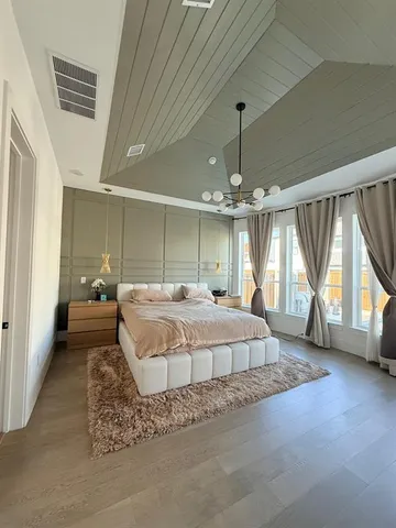 a spacious bedroom with a bed window and a chandelier