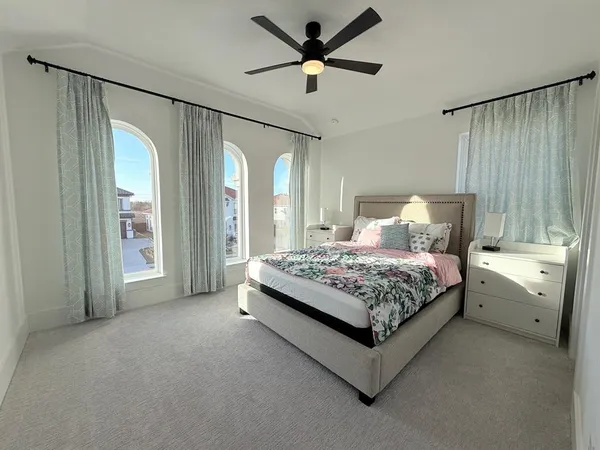 a bedroom with a large bed and a chandelier fan