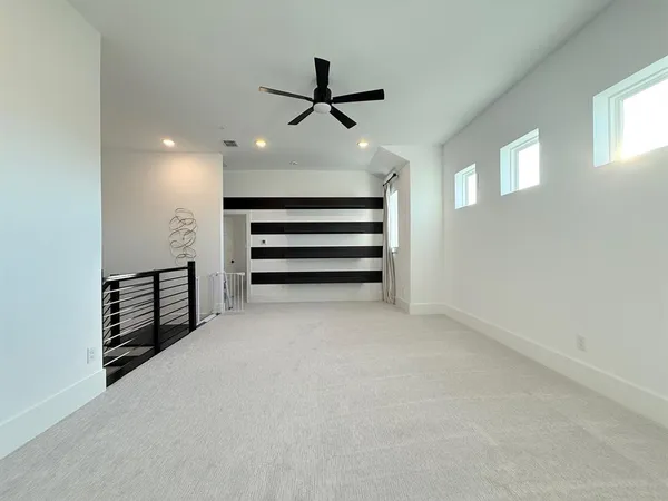 an empty room with windows and ceiling fan