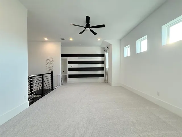 an empty room with windows and ceiling fan