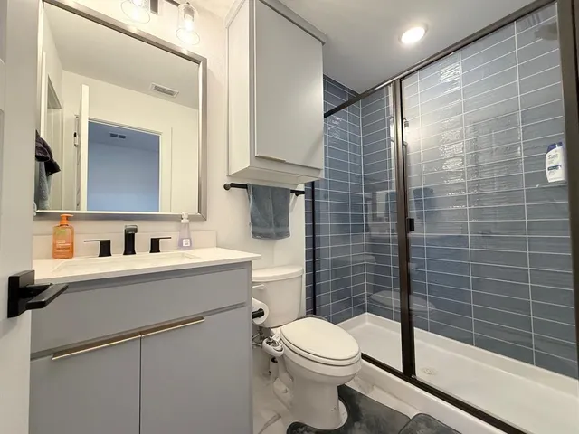 a bathroom with a toilet sink vanity and mirror