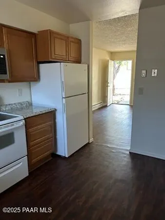 a kitchen with granite countertop wooden cabinets and white appliances