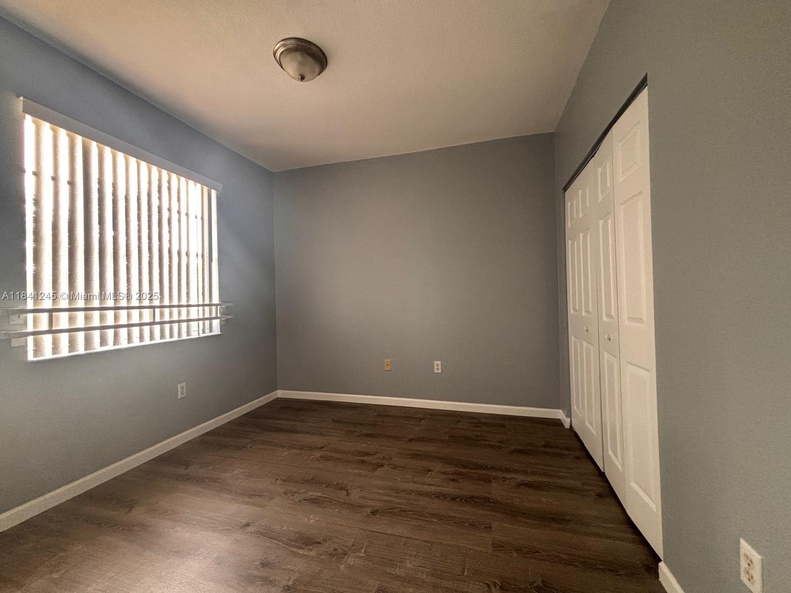 8491 Southwest 27th Street, Unit 101 Miramar, FL 33025 - Photo 8 of 10 a view of an empty room with wooden floor and a window