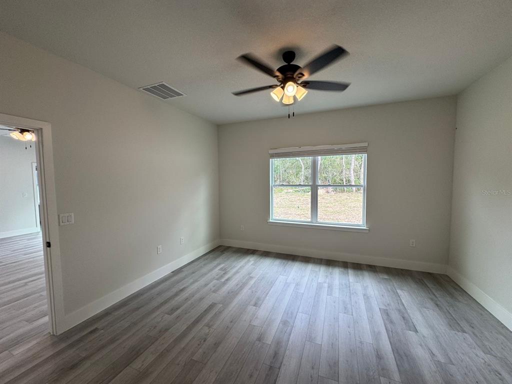 13385 Southwest 32nd Court Ocala, FL 34473 - Photo 13 of 20 an empty room with wooden floor fan and windows
