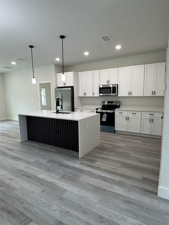 13385 Southwest 32nd Court Ocala, FL 34473 - Photo 3 of 20 a kitchen with kitchen island a sink stainless steel appliances and cabinets