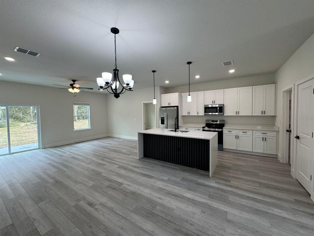 13385 Southwest 32nd Court Ocala, FL 34473 - Photo 4 of 20 a large kitchen with granite countertop a large counter top a refrigerator and a chandelier