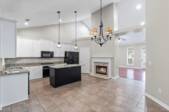 a large kitchen with kitchen island a stove a refrigerator a sink dishwasher a oven and a refrigerator with wooden floor