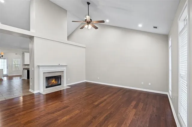 an empty room with wooden floor fireplace and windows