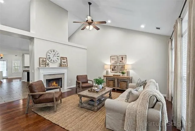 an empty room with wooden floor a ceiling fan a fireplace and windows