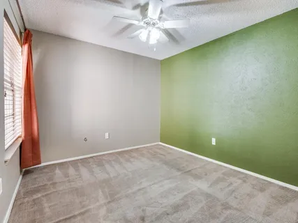 an empty room with a window and a ceiling fan