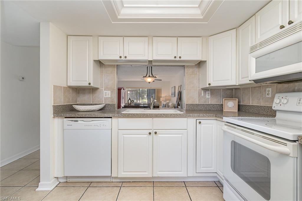 5535 Rattlesnake Hammock Road, Unit 103 Naples, FL 34113 - Photo 8 of 25 Light, neutral kitchen with white cabinetry.